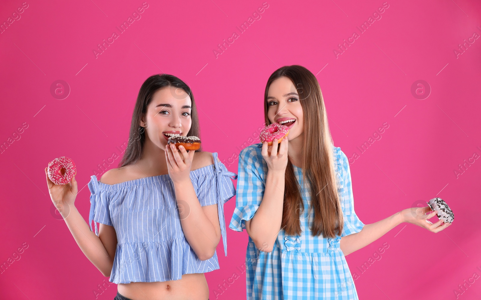 Photo of Beautiful young women with donuts on pink background