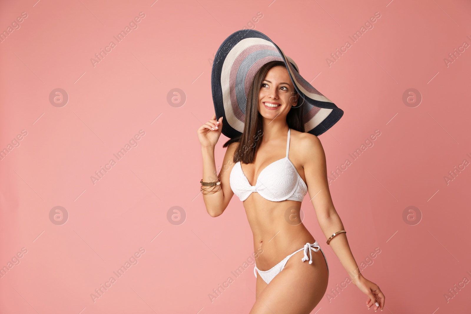 Photo of Pretty sexy woman with slim body in stylish  white bikini on coral background, space for text