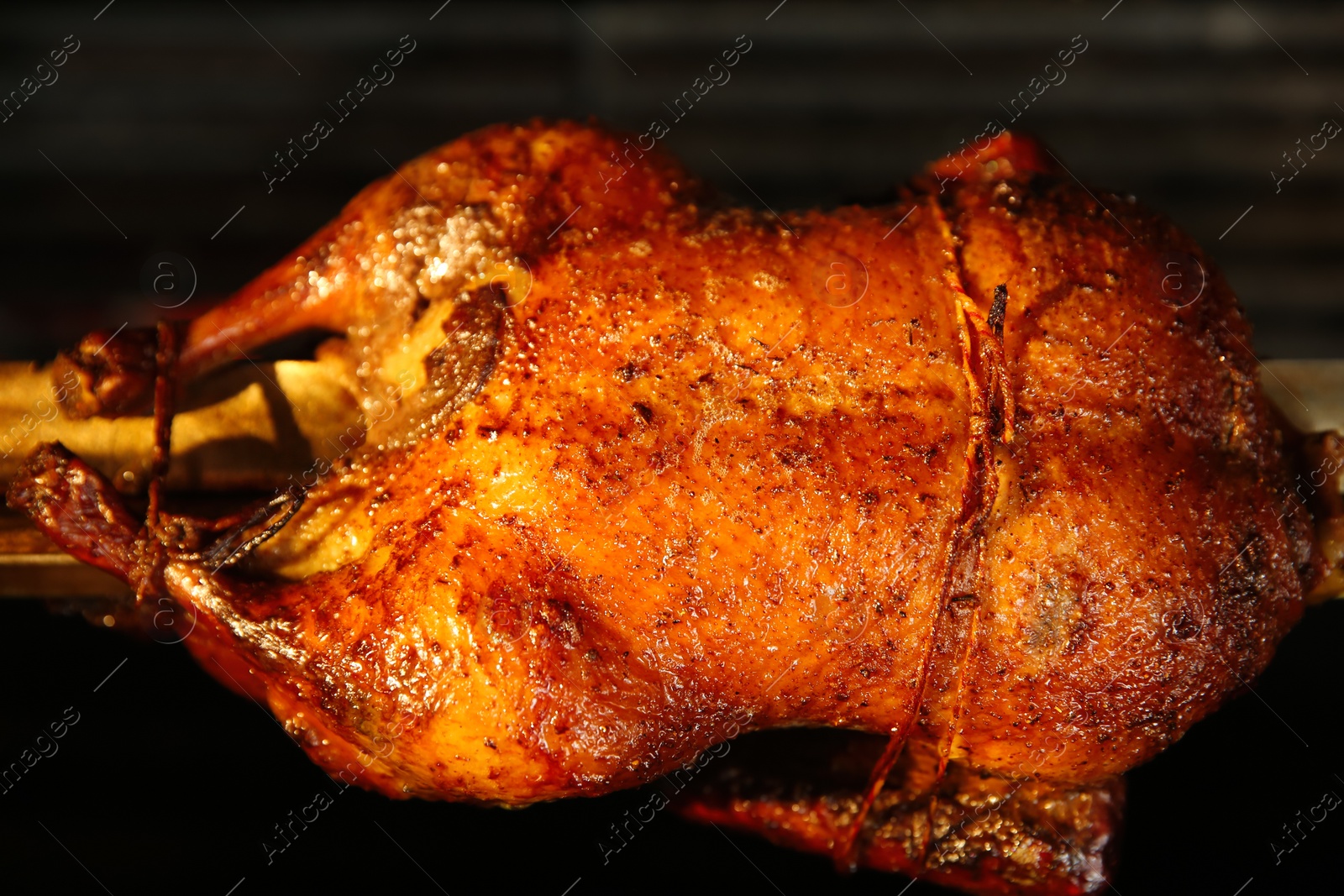 Photo of Grilling whole delicious duck in rotisserie machine, closeup