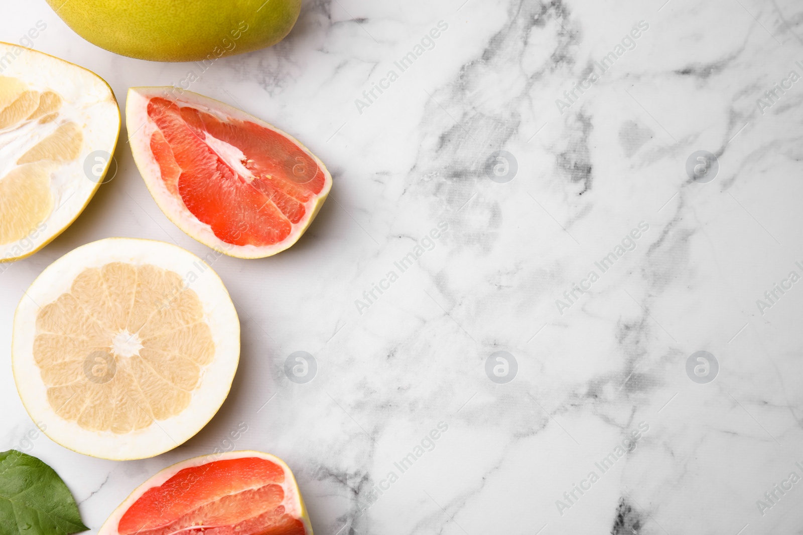 Photo of Different sorts of tasty pomelo fruits on white marble table, flat lay. Space for text