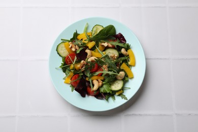 Photo of Tasty fresh vegetarian salad on white tiled table, top view