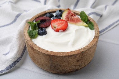 Photo of Bowl with yogurt, berries, fruits and mint on white tiled table, closeup