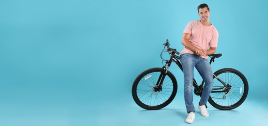 Image of Handsome young man with bicycle on light blue background, space for text. Banner design
