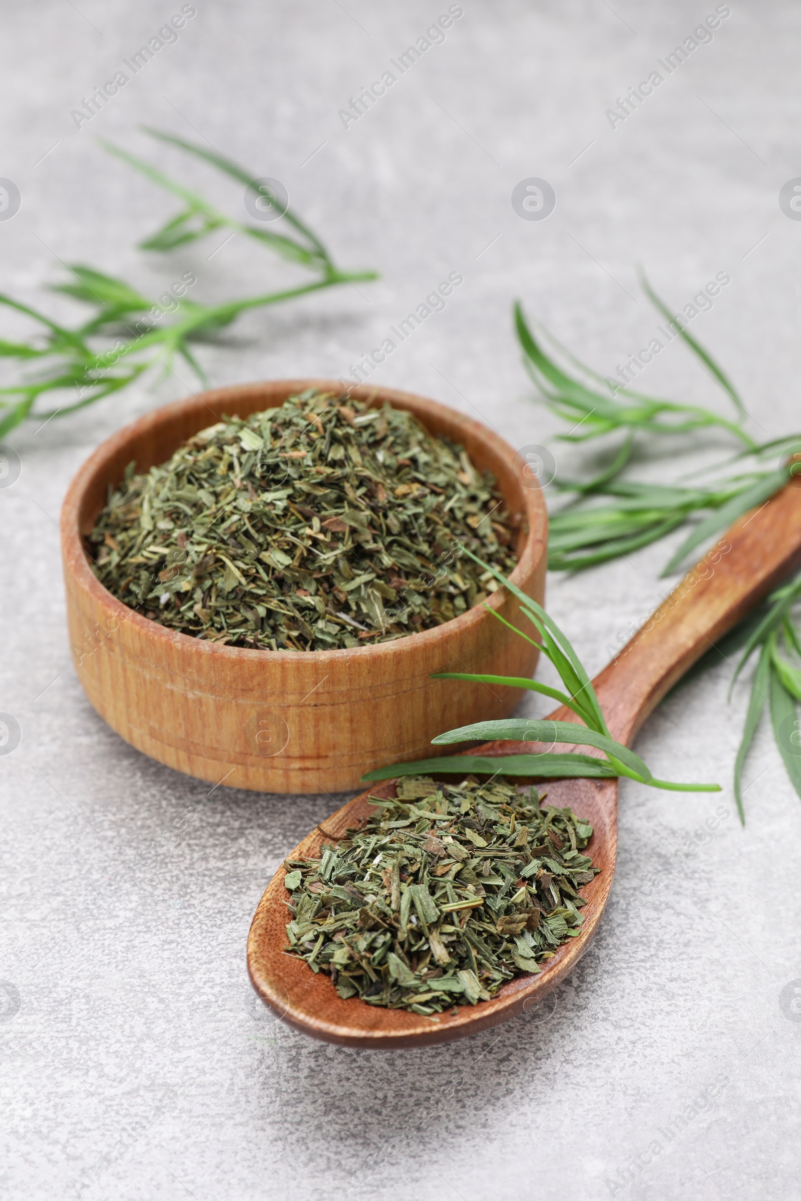 Photo of Dry and fresh tarragon on light gray textured table