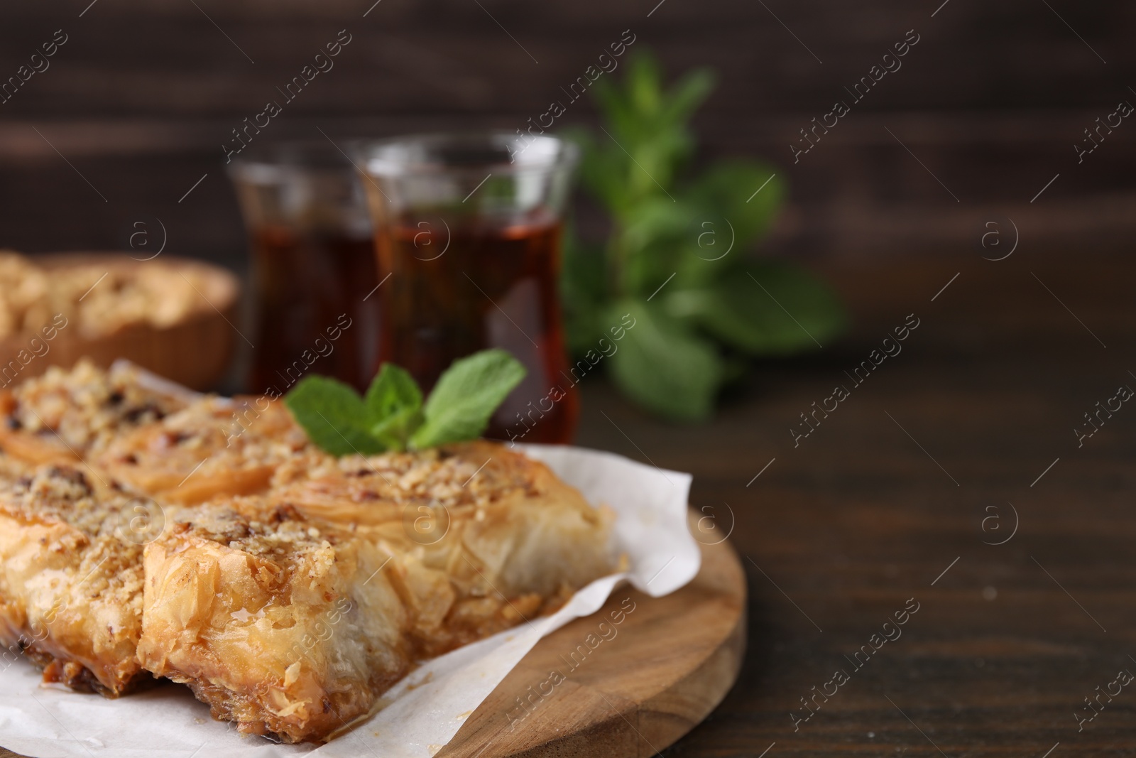 Photo of Eastern sweets. Pieces of tasty baklava on wooden table, closeup. Space for text