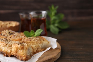 Photo of Eastern sweets. Pieces of tasty baklava on wooden table, closeup. Space for text