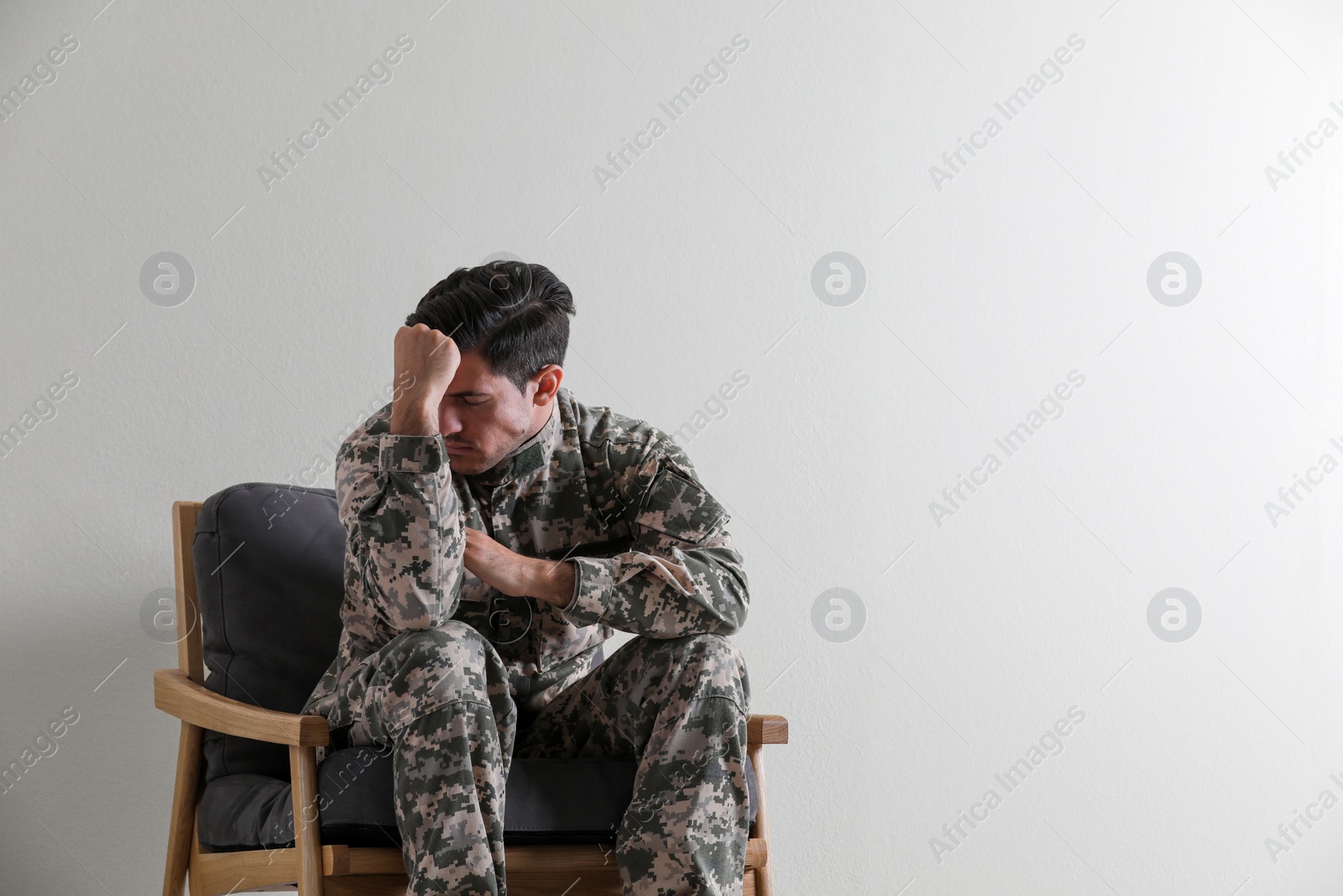 Photo of Stressed military officer sitting in armchair on white background. Space for text