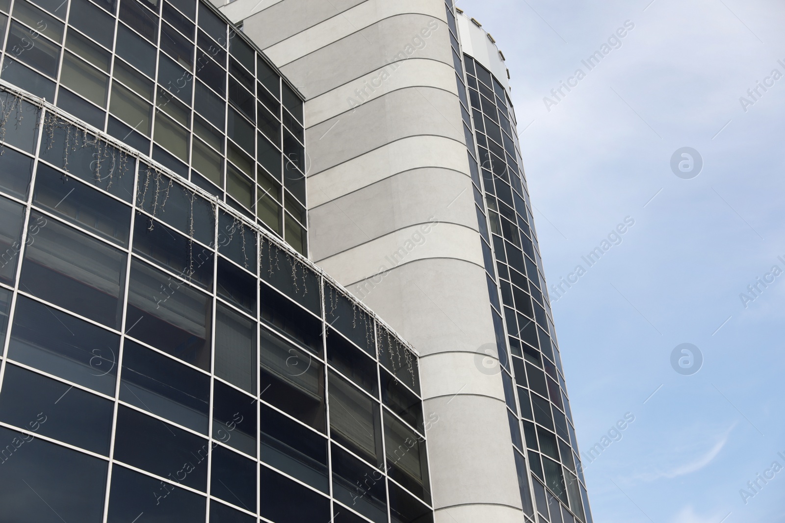 Photo of Modern building with tinted windows against sky, low angle view. Urban architecture