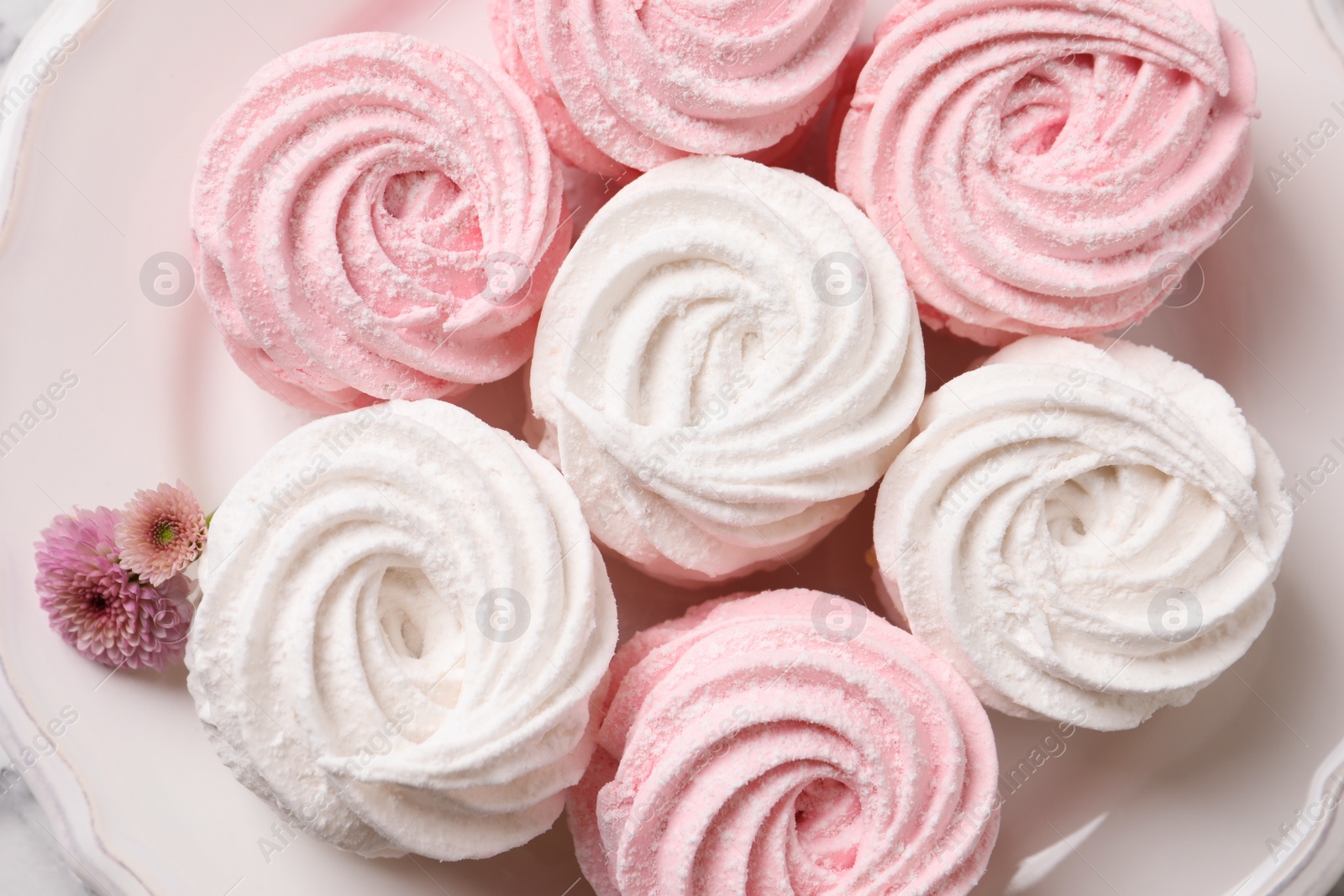 Photo of Closeup of delicious white and pink marshmallows on plate, top view