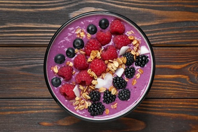 Photo of Delicious acai smoothie with berries and oatmeal on wooden table, top view