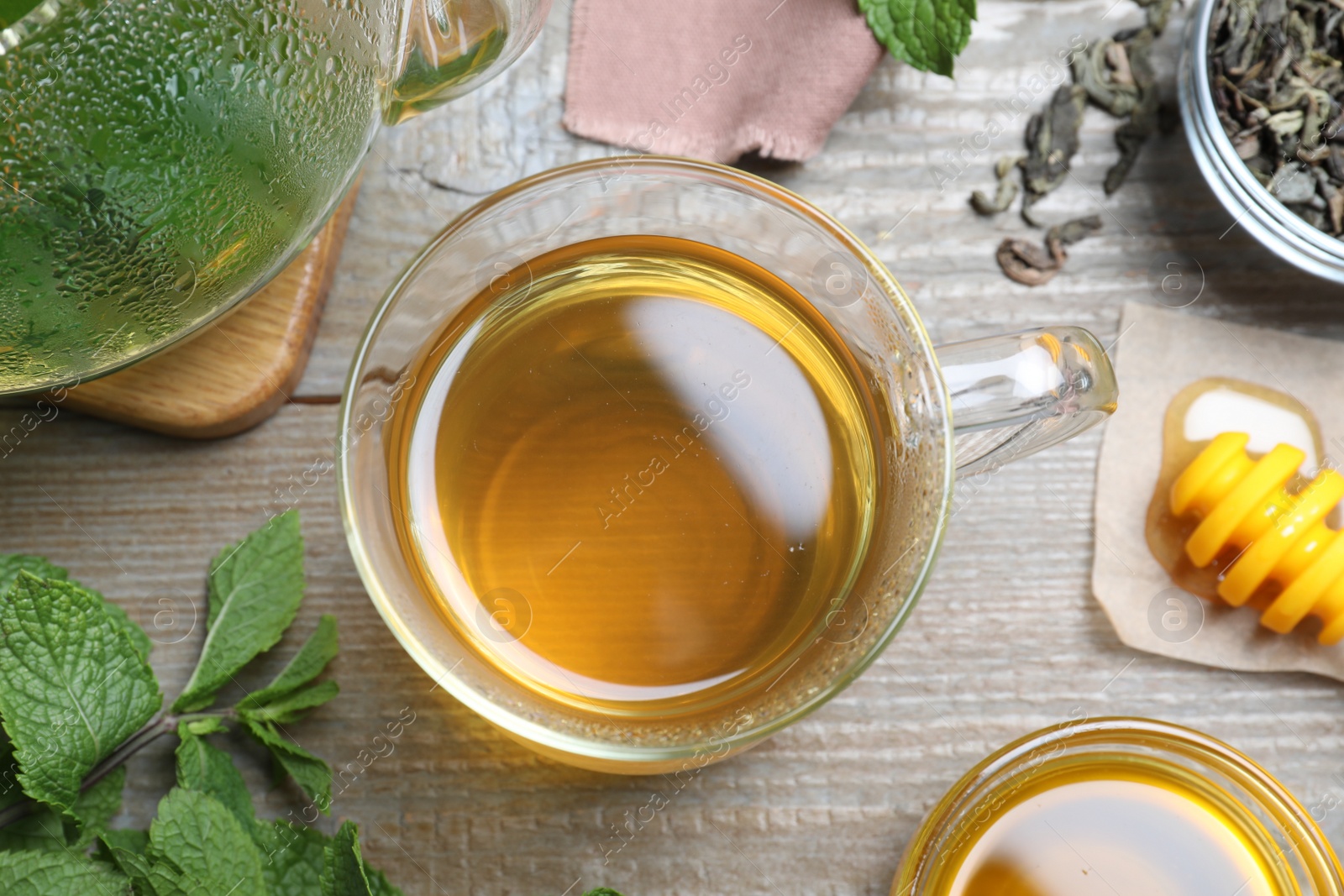 Photo of Flat lay composition with cup of hot aromatic mint tea on wooden table