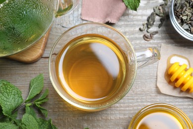 Photo of Flat lay composition with cup of hot aromatic mint tea on wooden table