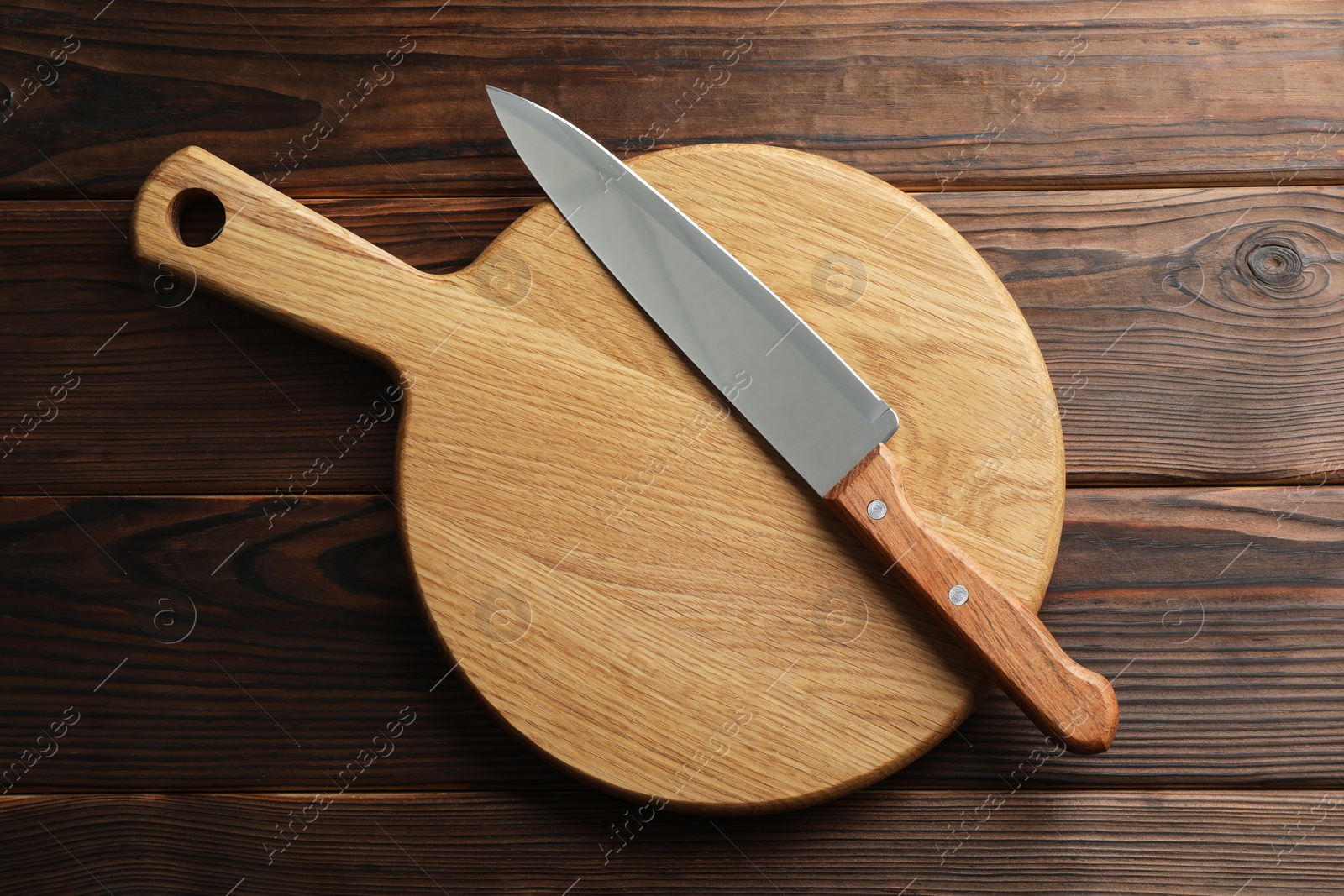 Photo of Knife and board on wooden table, top view