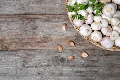 Wicker plate with fresh garlic on wooden background, top view