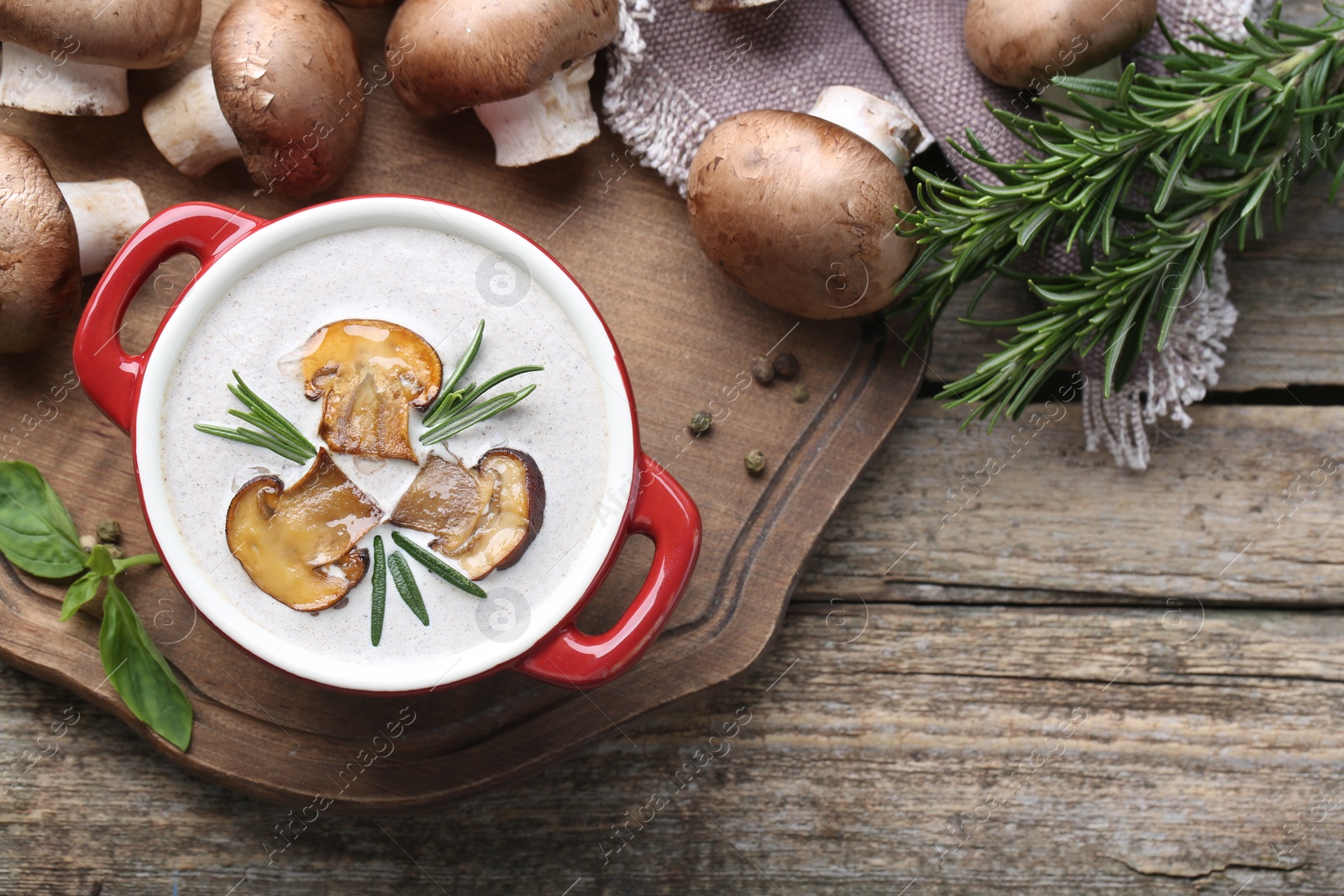 Photo of Delicious homemade mushroom soup in ceramic pot and fresh ingredients on wooden table, flat lay. Space for text