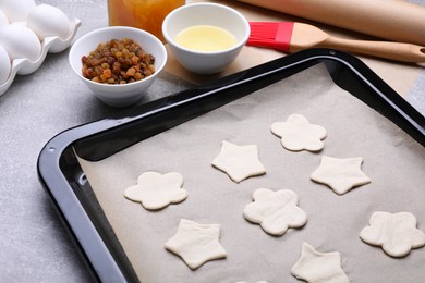 Photo of Baking pan with unbaked homemade cookies and parchment paper on light grey table