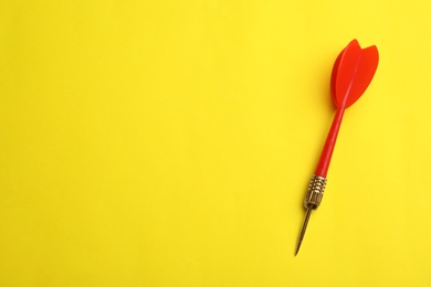 Photo of Red dart arrow on yellow background, top view with space for text