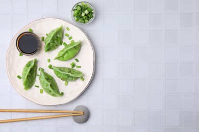 Delicious green dumplings (gyozas) served on white tiled table, flat lay. Space for text