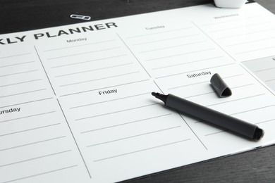 Photo of Timetable. Weekly planner and felt pen on black wooden table