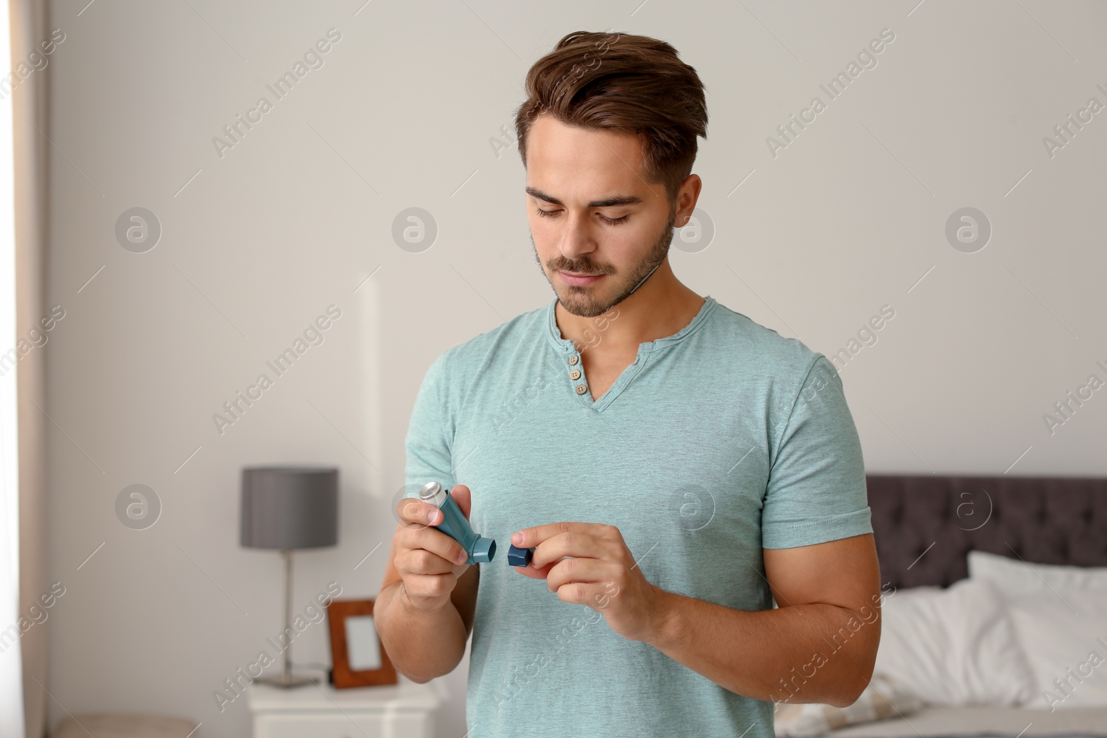Photo of Young man with asthma inhaler at home