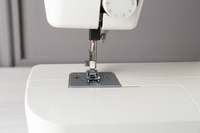 Photo of Sewing machine on white table near gray wall, closeup