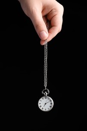 Photo of Psychotherapist with pendulum on black background, closeup. Hypnotherapy session