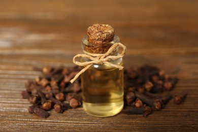 Essential oil and dried cloves on wooden table