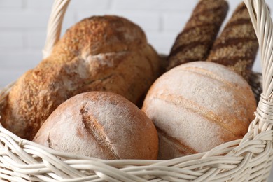 Photo of Different types of bread in wicker basket, closeup