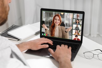 Image of Man having video chat with coworkers via laptop at white table, closeup