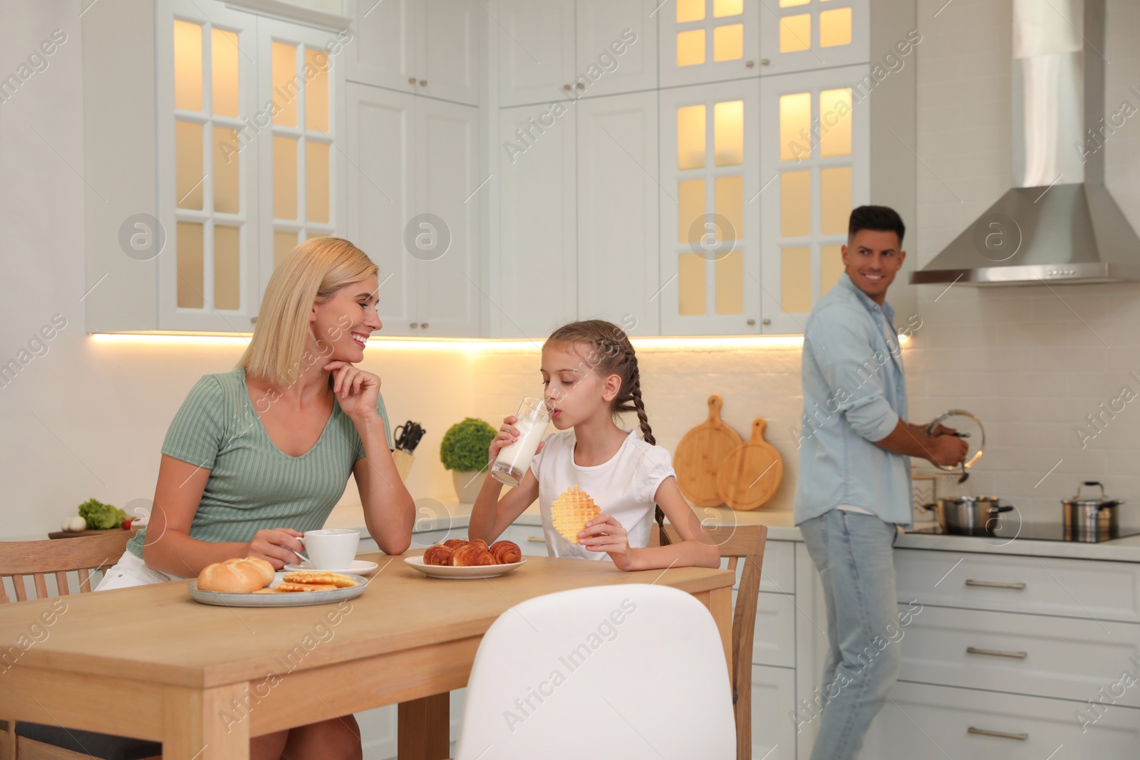 Photo of Happy family eating together in modern kitchen