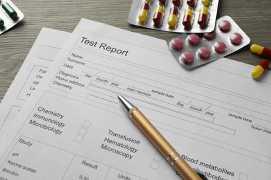 Photo of Drug test result form, pills and pen on wooden table, closeup
