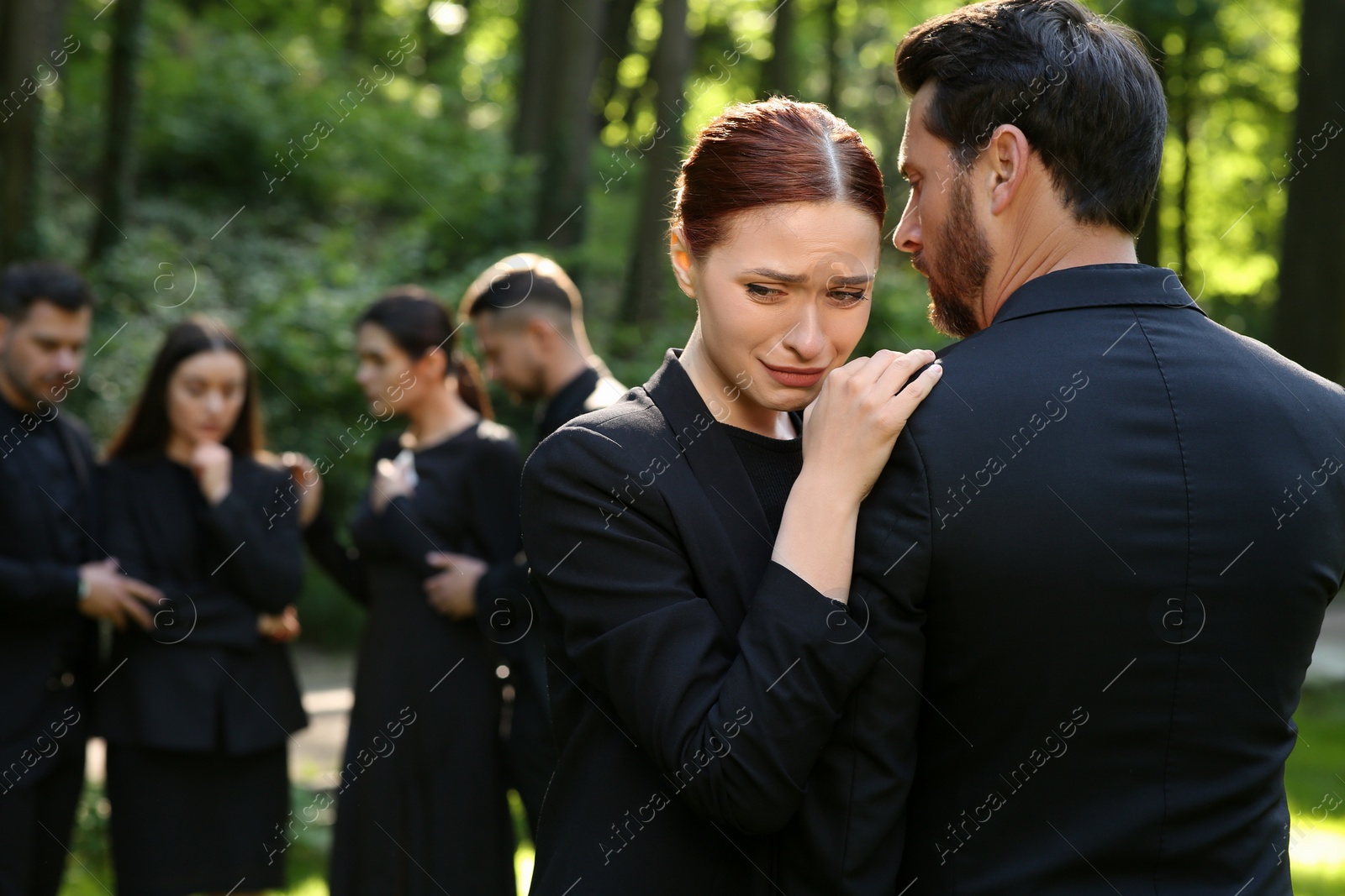 Photo of Sad people in black clothes mourning outdoors. Funeral ceremony