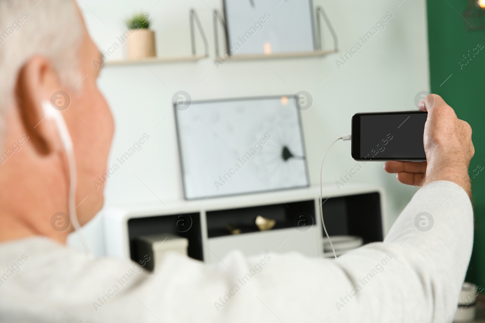 Photo of Man using video chat on mobile phone at home, closeup. Space for text