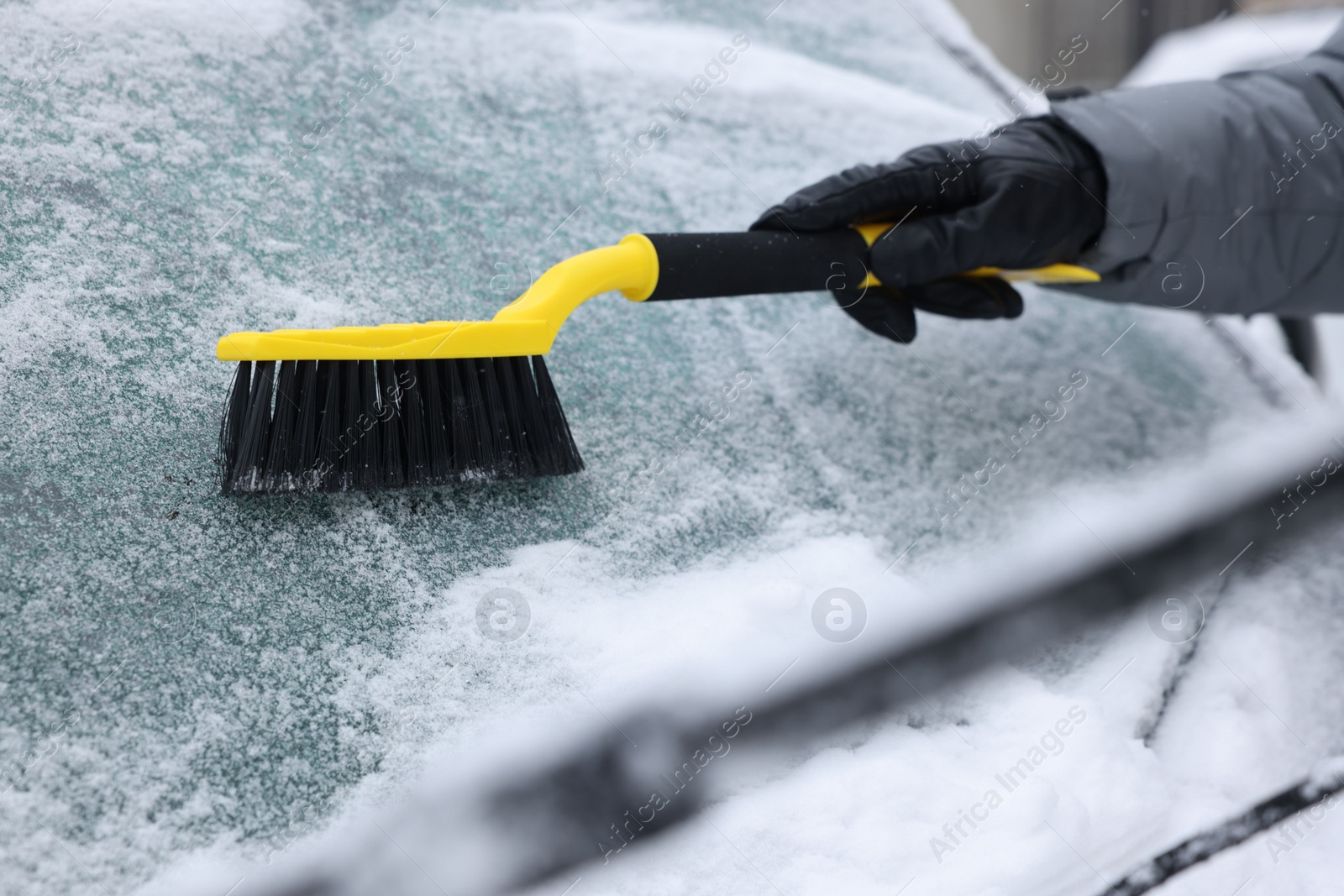 Photo of Man cleaning snow from car windshield outdoors, closeup