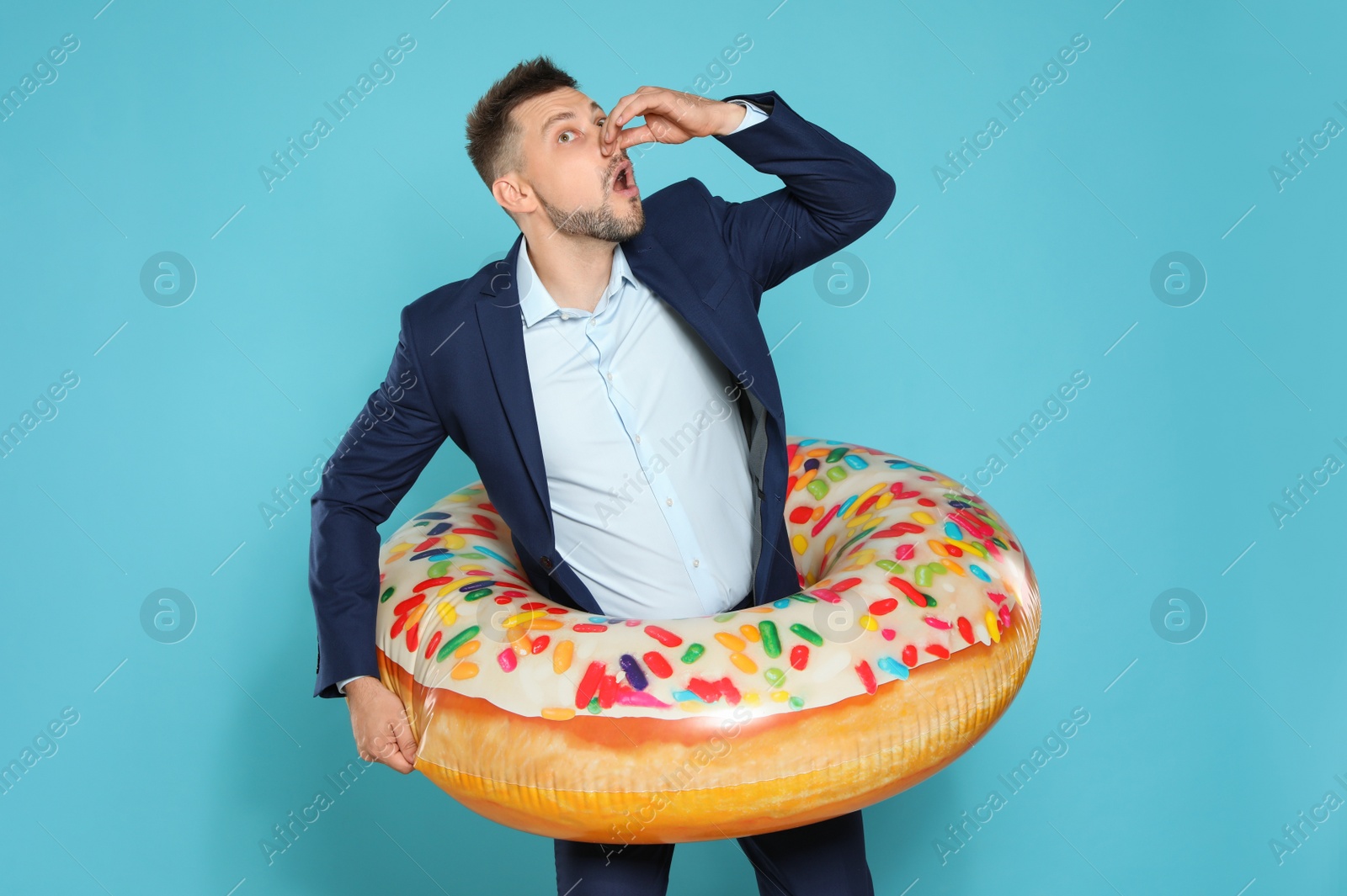 Photo of Funny businessman with bright inflatable ring on blue background