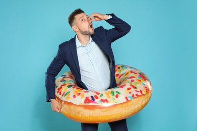 Funny businessman with bright inflatable ring on blue background
