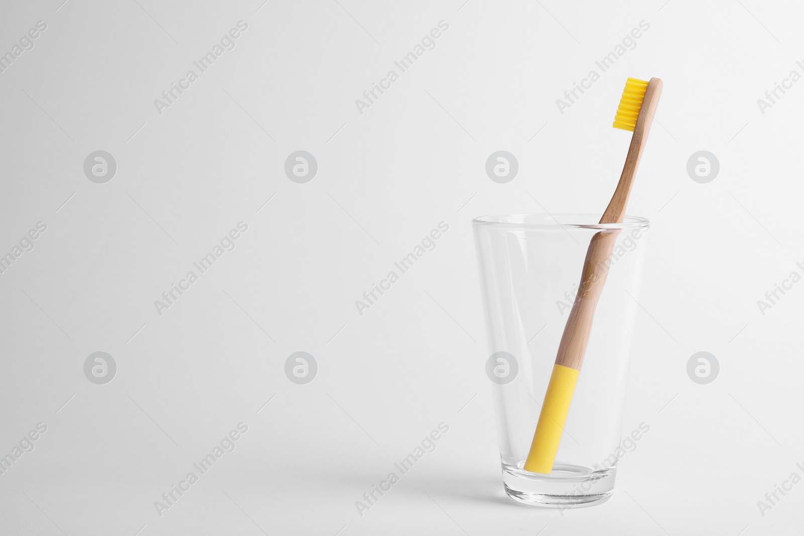 Photo of Glass with bamboo toothbrush on white background. Space for text