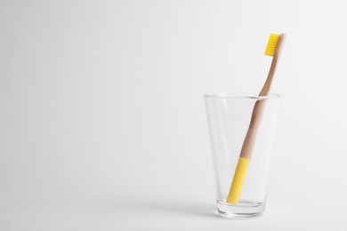 Glass with bamboo toothbrush on white background. Space for text