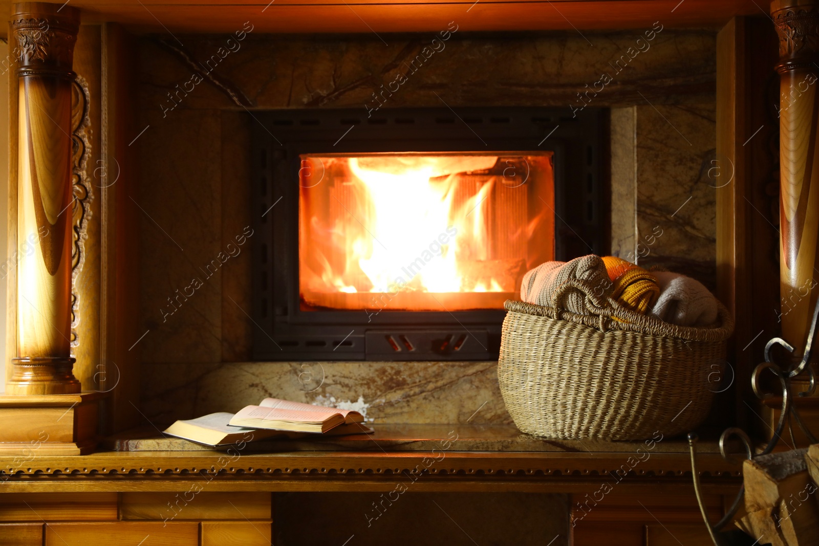 Photo of Sweaters, books and firewood near fireplace at home