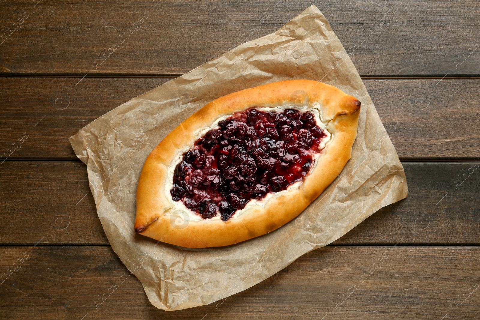 Photo of Delicious sweet cottage cheese pastry with cherry jam on wooden table, top view