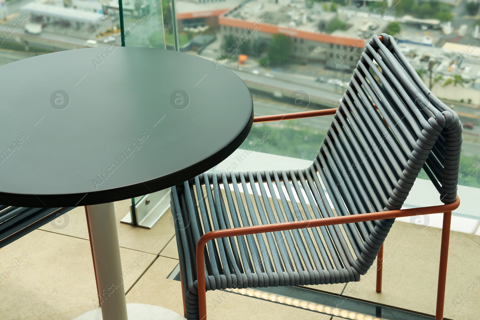 Photo of Coffee table and chair against picturesque landscape of city in cafe