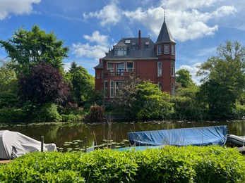 Beautiful view of house near river with moored boats on sunny day