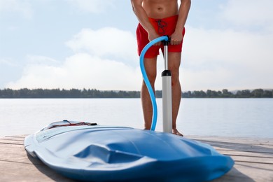 Man pumping up SUP board on pier, closeup. Space for text
