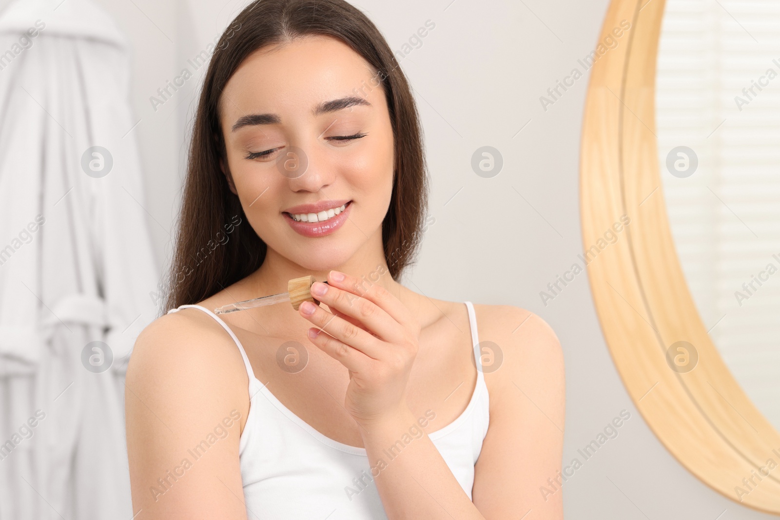 Photo of Woman applying essential oil onto shoulder in bathroom, closeup