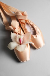 Photo of Ballet shoes. Elegant pointes and orchid flower on grey background, above view