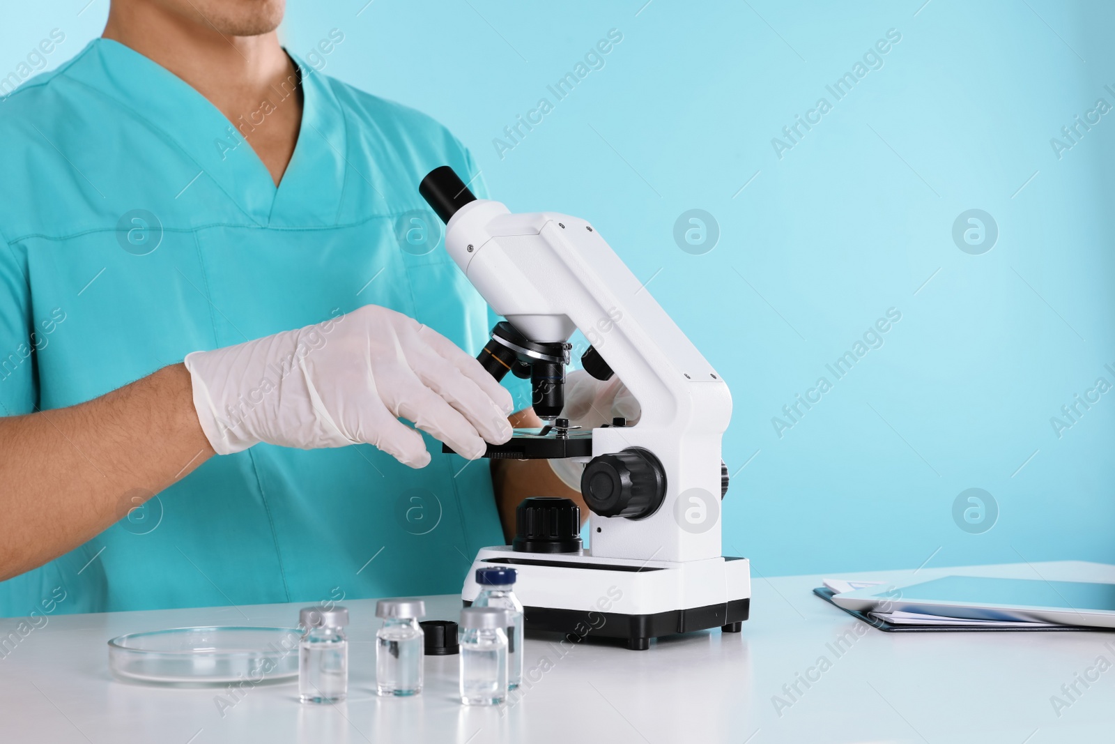 Photo of Male doctor using microscope at table, closeup with space for text. Medical object