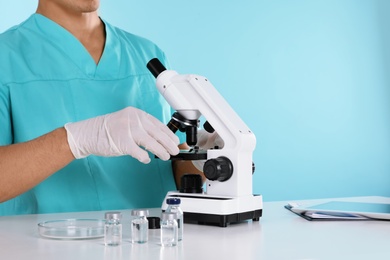 Photo of Male doctor using microscope at table, closeup with space for text. Medical object