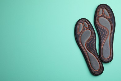 Photo of Pair of orthopedic insoles on turquoise background, flat lay. Space for text