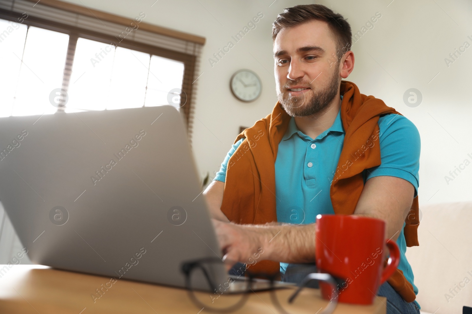 Photo of Young man using laptop at table indoors