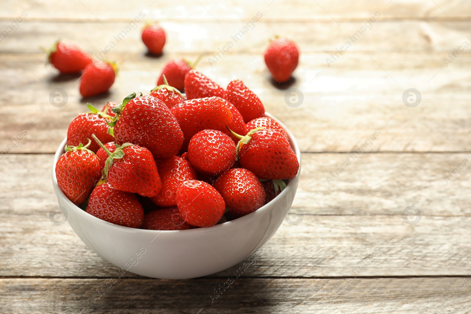 Photo of Bowl with fresh ripe strawberries on wooden table